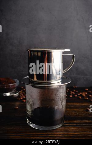 Brühen von heißem vietnamesischem Schwarzkaffee (Cà Phê den) mit einem Phin-Filter: Vietnamesischer Kaffee wird mit einem Tropffilter zubereitet Stockfoto