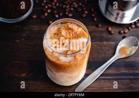 Vietnamesischer Joghurtkaffee (Sua Chua Cafe oder Cà Phê Sữa): Ein Glas vietnamesischer Eiskaffee mit gespritztem Joghurt mit Löffel und phin-Filter Stockfoto