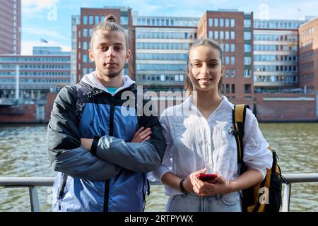 Außenporträt von Teenagern, Schülern, lächelnden Männern und Mädchen mit Rucksack, die die Kamera betrachten Stockfoto