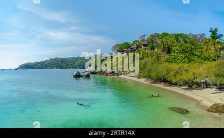 Bungalows fotografiert von der Fähre an der Küste in Ko Tao Thailand versteckt zwischen Palmen und Felsen und in Stufen zum Meer. Stockfoto