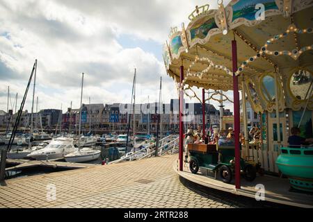 PAIMPOL, FRANKREICH, AUGUST 2023 - das alte Karussell und die Boote im touristischen Hafen, im Zentrum von Paimpol, einer charmanten Stadt in Cotes d'Armor, Bretagne, Stockfoto