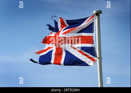 ZERRISSENE UND AUSGEFRANSTE UNION JACK FLAGGE AUF FAHNENMAST MIT BLAUEM HIMMEL RE BREXIT DIE UNION FLAGGEN PATRIOT PATRIOTIC UK Stockfoto