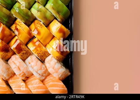 Ein Set heller, mehrfarbiger Sushi-Brötchen mit Garnelen, Lachs, Aal, Avocado, Käse in Kunststoffverpackung, auf hellem Hintergrund, Draufsicht, Nahaufnahme, c Stockfoto