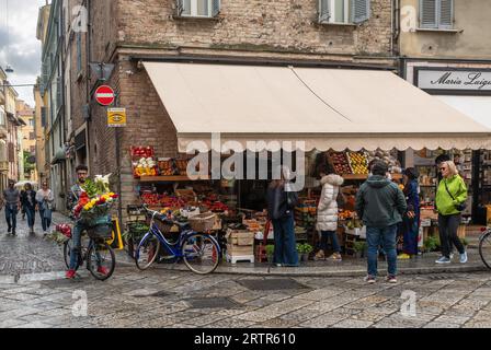 Menschen vor einem Gemüsehändler mit Obst und Gemüse auf dem Bürgersteig in der Altstadt im Frühjahr, Parma, Emilia-Romagna, Italien Stockfoto