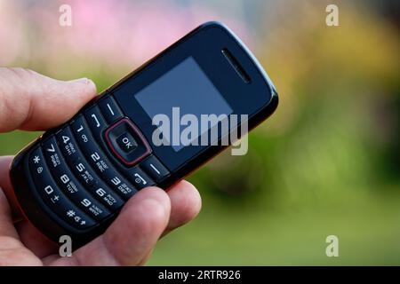 Ein altes Mobiltelefon mit Druckknopf in der Hand Stockfoto