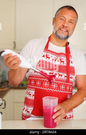 Küchenchef bereitet Smoothie zu Hause zu und gießt den Milchshake nach dem Kochen in das Glas. Stockfoto