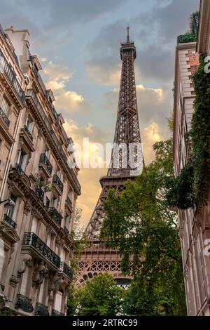 Tour Eiffel am Himmel mit farbigen Sonnenuntergangswolken zwischen historischen Gebäuden auf der Rue de l'Université in Paris. Vertikale Ansicht Stockfoto