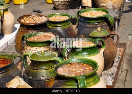Ungarisches Gulasch, das in grün-braunen Tontöpfen durch ein Feuer im Freien gekocht wird Stockfoto