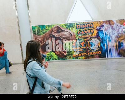 Palma, Spanien - 22. Juni 2023: Mutter und Sohn gehen in der Nähe einer Werbetafel am Flughafen Palma de Mallorca mit Port Cristo Dino und Höhlen Stockfoto