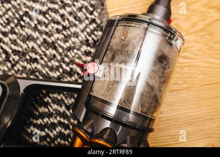 Bei einer Nahaufnahme werden die komplizierten Komponenten eines Staubsaugers sichtbar. Der Staubbehälter ist voller Staub, Katzenhaare und Hundefell. Stockfoto