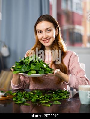 Glückliches Mädchen, das köstlichen Spinatsalat aus der Nähe macht Stockfoto