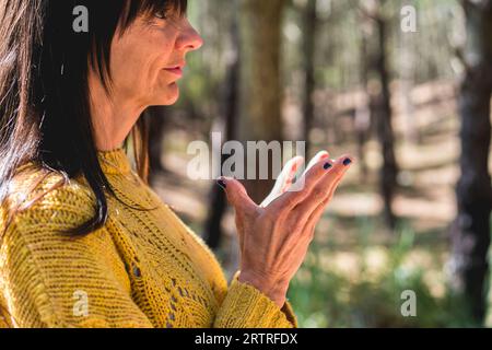 Seitenansicht von Padma Mudra, ausgeführt von einer Frau über Naturhintergrund Stockfoto