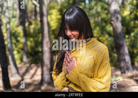 Die Frau meditiert mit den Händen, die im Wald eingeschlossen sind. Stockfoto