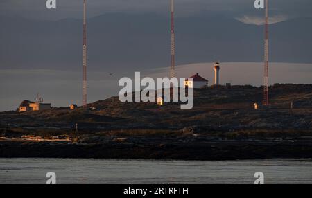 Der Trial Islands Leuchtturm in der Juan de Fuca Straße, der am frühen Morgen von Kitty Islet in Oak Bay, British Columbia, Kanada aus gesehen wird. Stockfoto