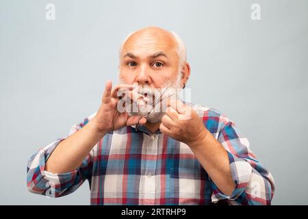 Friseurschere. Friseurladen-Konzept. Mann mittleren Alters. Porträt eines alten Glatze Mann bärtig mit grauem Schnurrbart. Stockfoto