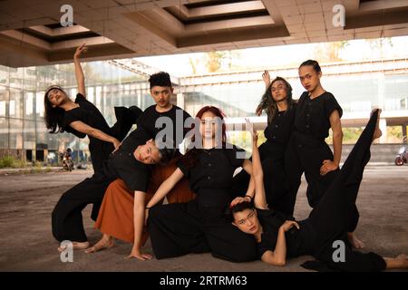 Eine Gruppe asiatischer Männer posiert fröhlich mit ihren Freunden, während sie schwarz in einem alten Gebäude tragen Stockfoto