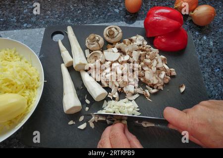 Schwäbische Küche, Zubereitung von deftigem Kartoffelstrudel, Petersilienwurzel, Schnittgemüse zum Füllen, Pilze, Kartoffeln auf der Rückseite gekocht und geschält Stockfoto