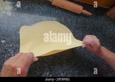 Schwäbische Küche, Zubereitung von deftigem Kartoffelstrudel, Herausziehen von rohem Kartoffelteig, Verarbeitung, Rollnadel, Arbeitsfläche, Herstellung von salzigem Strudel mit Gemüse Stockfoto
