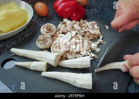 Schwäbische Küche, Zubereitung von deftigem Kartoffelstrudel, Petersilienwurzel, Schnittgemüse zum Füllen, Pilze, Kartoffeln auf der Rückseite gekocht und geschält Stockfoto