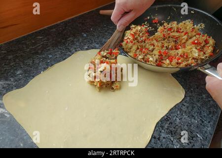 Schwäbische Küche, Zubereitung von deftigem Kartoffelstrudel, roher Kartoffelteig gefüllt mit Gemüse, Verarbeitung, geröstetes Gemüse, roter Pfeffer, Petersilie Stockfoto