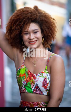 Porträt einer schönen rothaarigen Frau, die lange Kleider trägt und auf einer Kopfsteinpflasterstraße steht. Glücklicher Reisender. Stockfoto