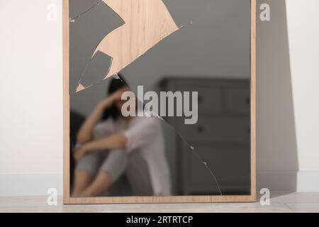Psychische Probleme. Verschwommenes Spiegelbild einer depressiven Frau im zerbrochenen Innenspiegel Stockfoto