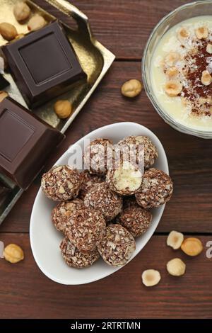 Köstliche süße Schokoladenbonbons und Zutaten auf Holztisch, flach gelegt Stockfoto