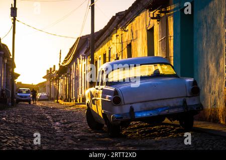 Sonnenuntergang Licht am späten Nachmittag auf der wunderschönen Straße mit einem weißen Oldtimer in Trinidad, Kuba Stockfoto