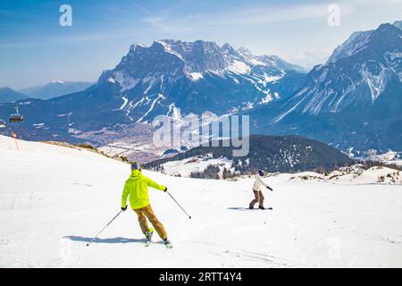 Skifahrer und Snowboarder auf der Panoramalauf mit Blick auf die Zugspitze, das Skigebiet Grubigstein, Lermoos, Tirol Stockfoto