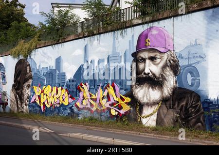 Karl Marx als kapitalistischer und obdachloser Mann in Gegenüberstellung, Porträts vor der Skyline der Großstadt, sozialkritische Wandmalerei der Straßenkünstler Stockfoto