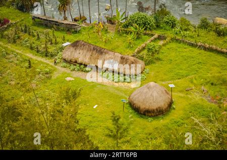 Foto von einfachen Häusern aus Holz und Stroh in der Nähe des Flusses, umgeben von Grün in Trikora, Papua, Indonesien. In dieser Region kann man sich nur treffen Stockfoto