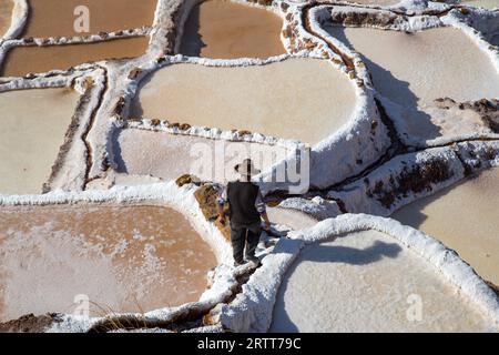 Maras, Peru, 11. Oktober 2015: Mann, der zwischen Salzverdunstungsbecken in den Salzminen von Maras spaziert Stockfoto
