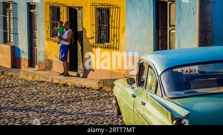 Trinidad, Kuba am 30. Dezember 2015: Kubanischer Vater mit Sohn neben dem Taxi im Morgenlicht Stockfoto