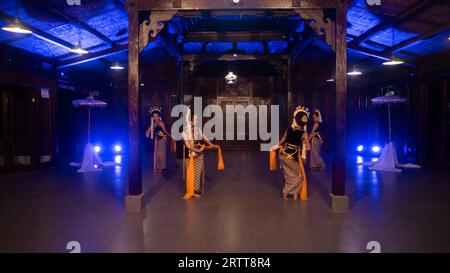 Eine Gruppe javanischer Tänzer tanzt nachts in einem Pavillon mit braunem Holz Stockfoto