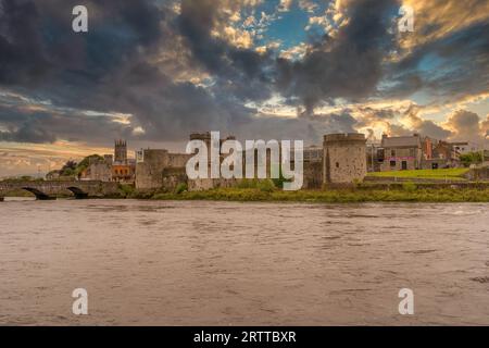King John Castle in Limerick Irland am Ufer des Shannon River neben der Thomond Bridge mit dramatischem Sonnenuntergang bewölktem Himmel Stockfoto