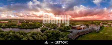 Panoramablick auf die Living Bridge, kurvenreiche moderne Fußgängerüberquerung über den Shannon River an der Universität von Limerick mit atemberaubendem Sonnenuntergang Stockfoto