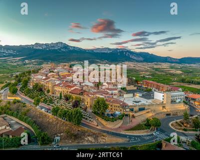 Blick aus der Vogelperspektive auf Laguardia mittelalterliches befestigtes Dorf auf einem Hügel, umgeben von Weingütern in der spanischen Region Rioja, mit farbenfrohem Sonnenuntergang Stockfoto