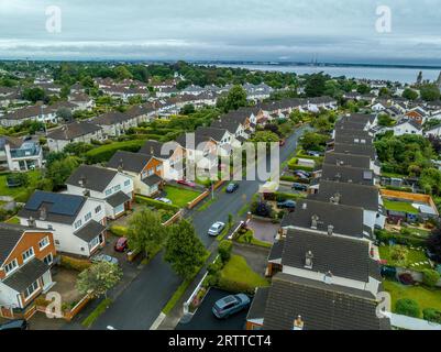 Aus der Vogelperspektive auf das irische Viertel der oberen Mittelklasse mit Einfamilienhäusern, die sich entlang einer Straße auf dem teuren Immobilienmarkt in Dublin aneinander Reihen Stockfoto