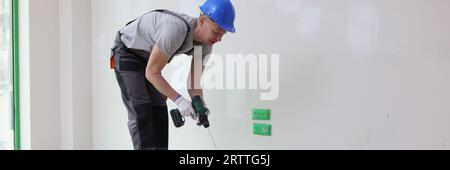 Männlicher Dekorator mischt Farbe im Eimer mit dem Mischer. Stockfoto