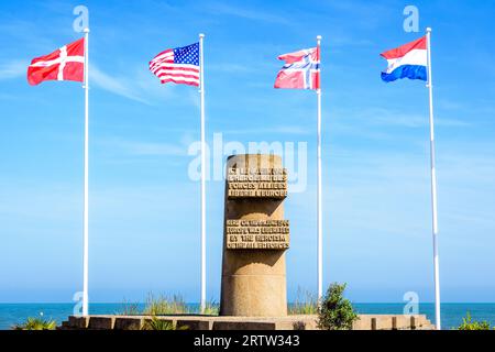 Signaldenkmal in Bernières-sur-Mer, Frankreich, errichtet im Jahr 1950 auf der Anlegestelle der Normandie im Zweiten Weltkrieg am Juno Beach, umgeben von den Flaggen der Alliierten. Stockfoto