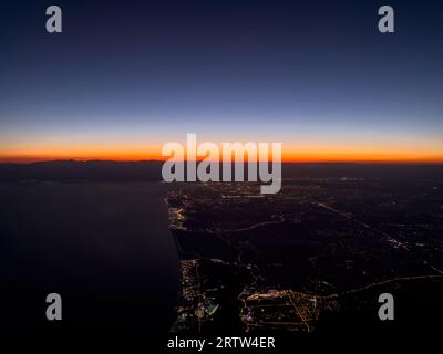 Blick auf die Stadt Antalya und die Lichter der Stadt vom Flugzeug bei Sonnenuntergang Stockfoto