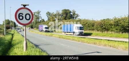 Schnell fahrende schwere Nutzfahrzeuge passieren ein Schild mit Geschwindigkeitsbegrenzung Stockfoto