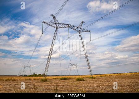 Kraftübertragungsturm in der Ukraine im Sommer. Oberleitungen der Hochspannungs-Stromübertragungsleitung stützen sich im Sommer durch ein Feld mit Mais Stockfoto