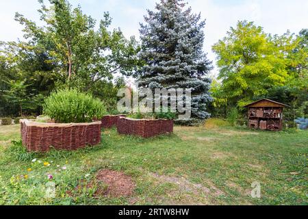 Hochgewachsene Korbbeete und Insektenhotel im Park von Lenck-Villa, Sopron, Ungarn Stockfoto