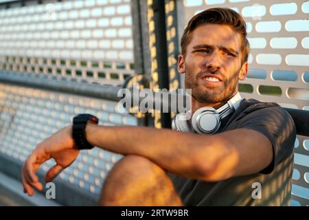 Ein junger, fit Mann nimmt nach dem Training im Freien eine kleine Pause ein. Fitness Sport People Lifestyle Konzept Stockfoto