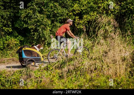 Neuoetting, Deutschland – Sptermber10,2023: Ein Mann macht einen Spaziergang auf seinem Fahrrad mit seinem Hund, der hinten in einem Anhänger sitzt. Stockfoto