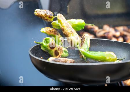 Padron Peppers, Herbon Pepper, geschwenkt, in einer Pfanne auf einem Grill gebraten, Tapas, scharfe Überraschungspeprika, kleine grüne Paprika, Stockfoto