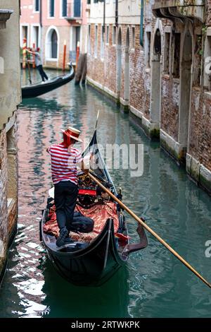 Malerischer Blick auf einen Kanal in Venedig, Italien, mit Gondel und dem berühmten roten gestreiften Hemdgondolier Stockfoto