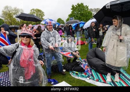 Eine große Menschenmenge, die dem Regen trotzt, um die Krönung von König Karl III. Auf einem riesigen Fernsehbildschirm zu sehen. Hyde Park, London, Großbritannien. 6. Mai 2023 Stockfoto