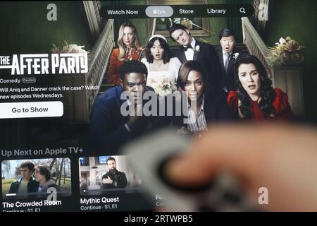 Die Apple TV+ App auf dem fernsehbildschirm hebt die Fernsehserie The Afterparty hervor, mit dem Schatten einer Person, die eine Apple TV-Fernbedienung vor sich hält. Stockfoto